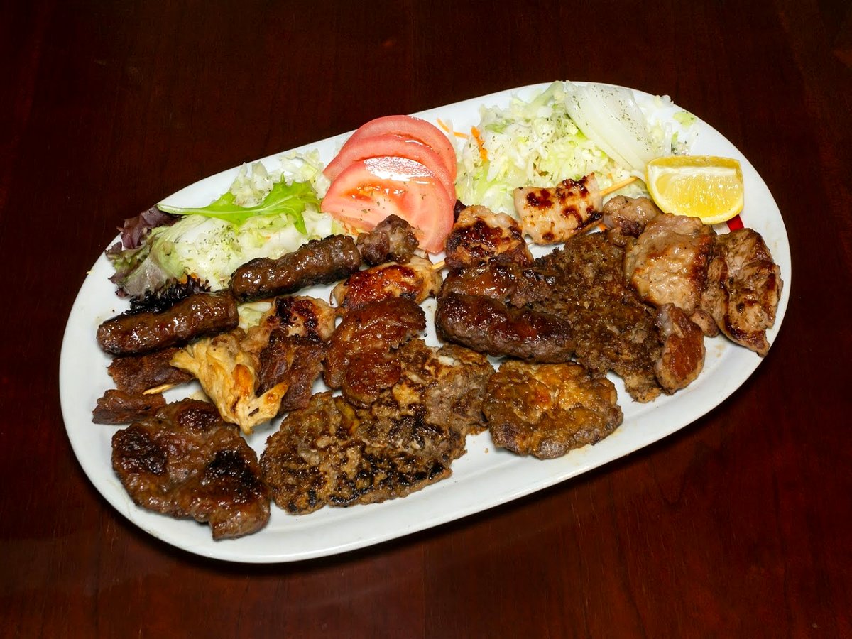Mixed Balkan grill platter with cevapi, grilled meats, chicken and cabbage salad